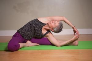 laurel doing a yoga pose leaning to the left with right arm over her head and clasped with left hand