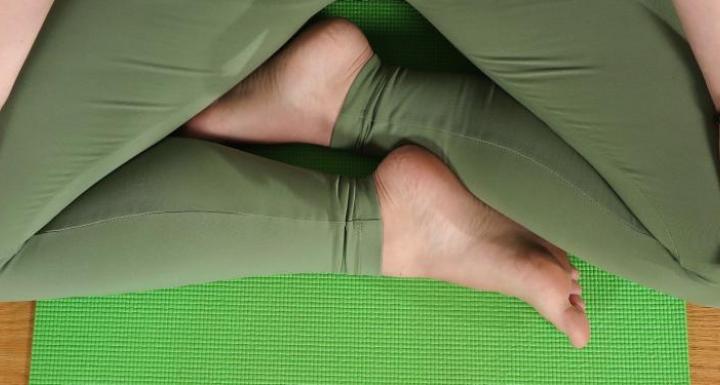 top view of meghan in sitting yoga pose with feet crossed, hands resting on legs with palms up